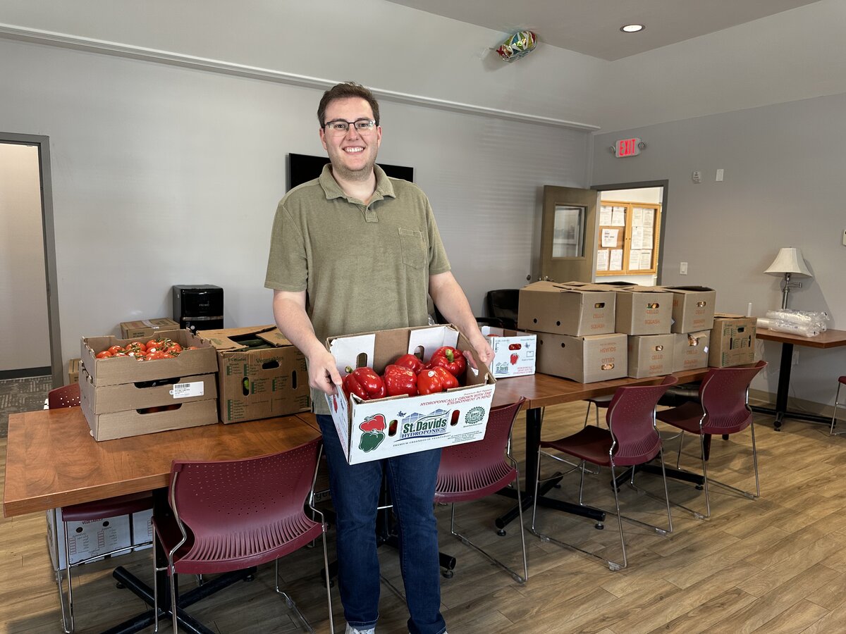 Ben Sigel holding a box of fresh red peppers at a Full Belly Foods delivery